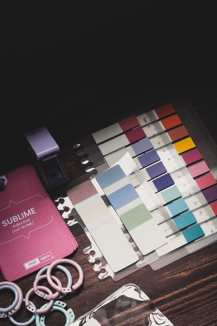 Colorful design swatches and accessories arranged creatively on a dark table.